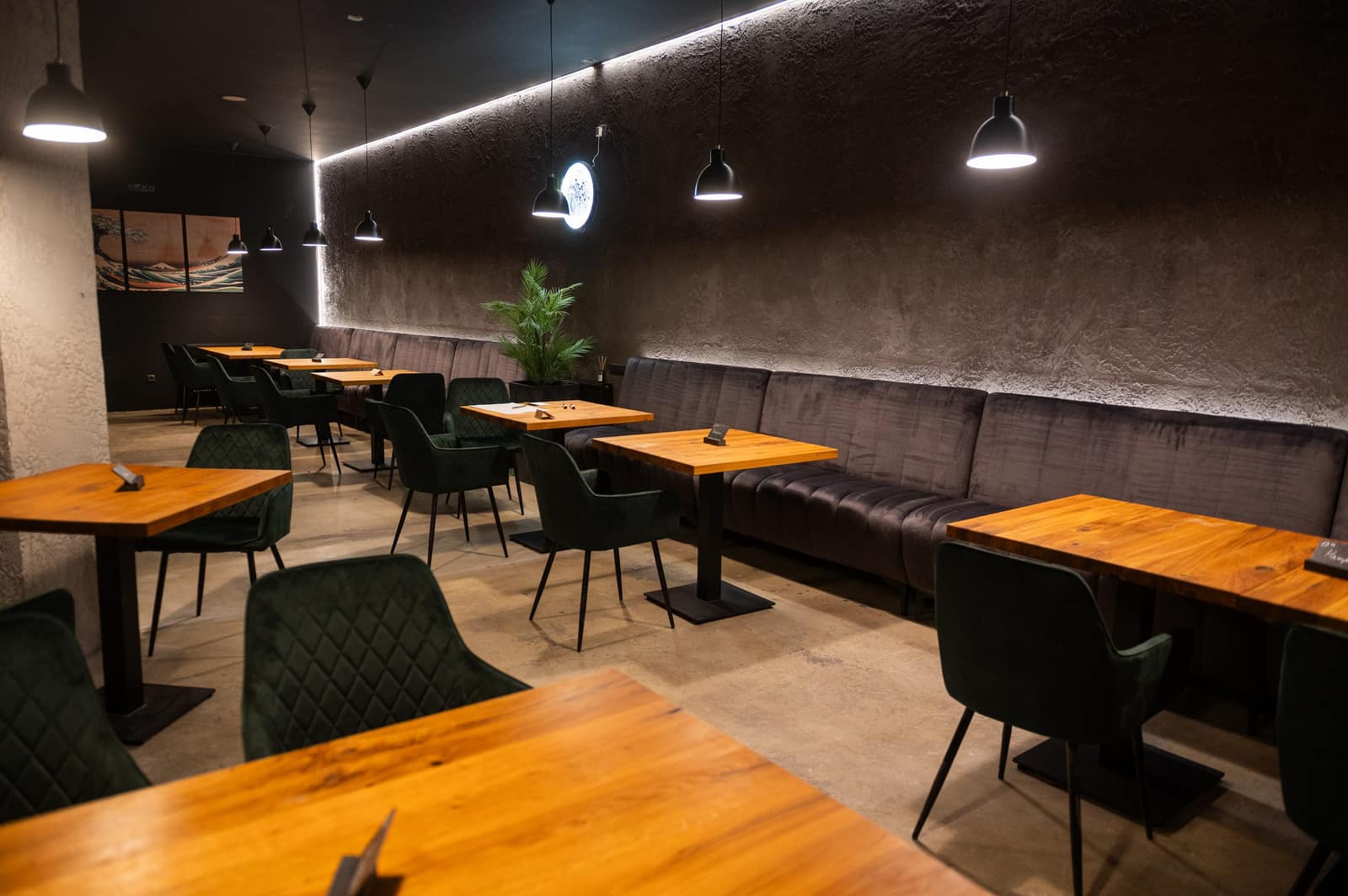 Interiér restaurace The Moon Plzeň – dřevěné stoly, sametové pohovky a závěsná světla