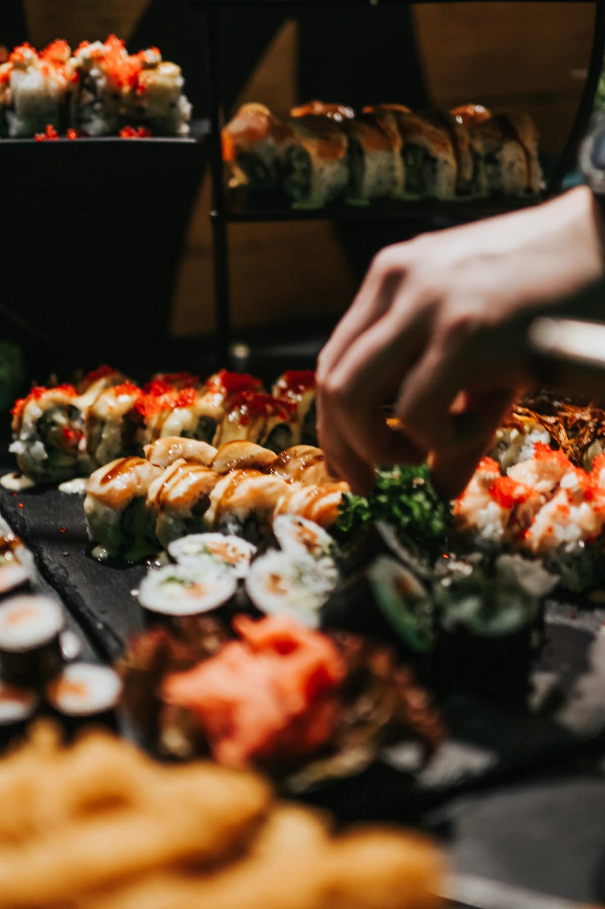 Příprava sushi rolek na servírovacím tácu